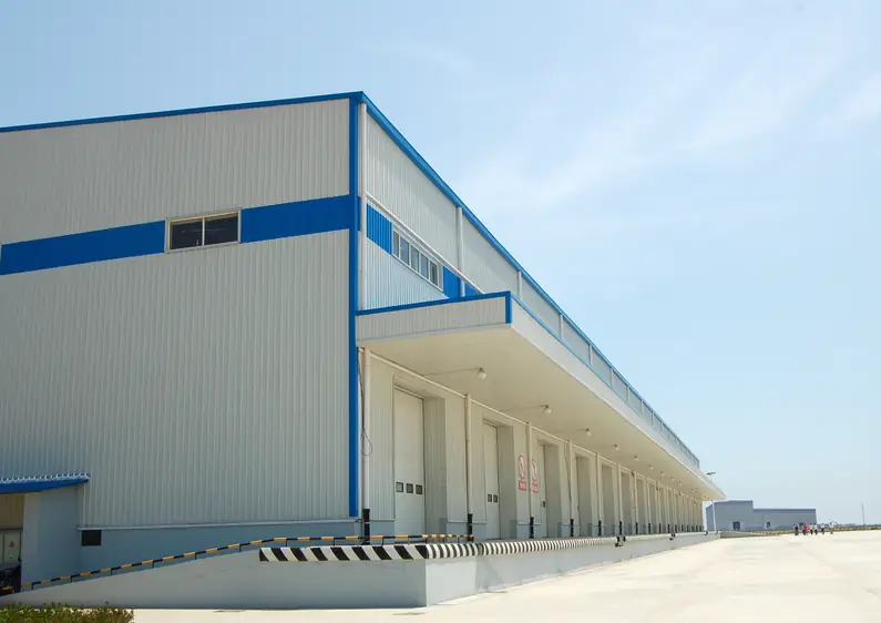 Large metal warehouse with a white and blue exterior and loading docks