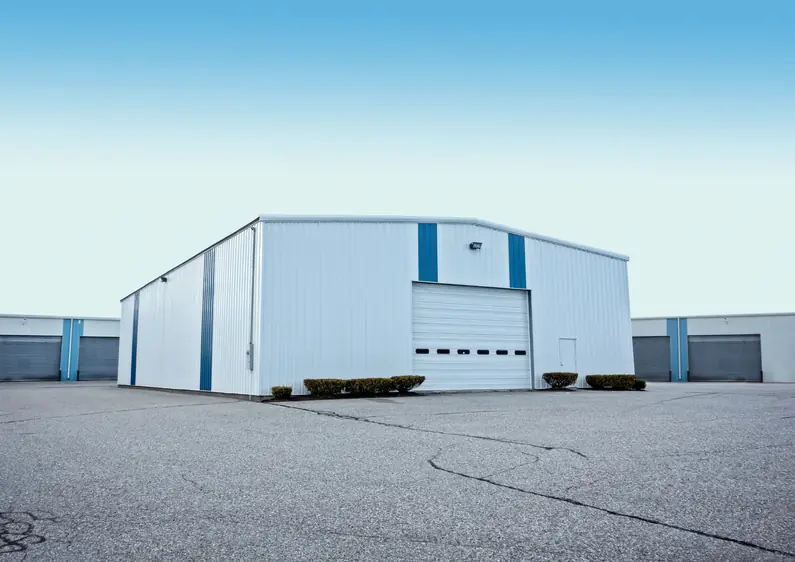 White steel building with a roll-up door and blue trim