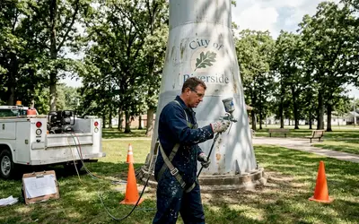 Painter spraying a city water tower base in a park