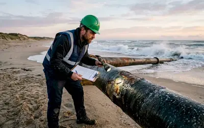 Inspector checking a coated pipeline on a beach