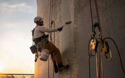 Rope access technician painting a water tower